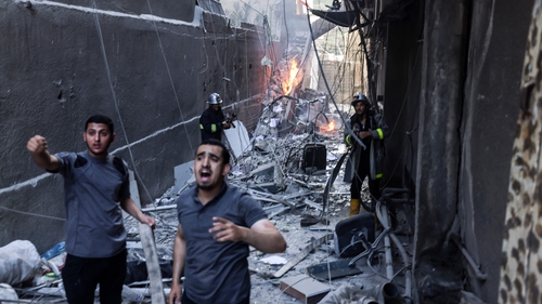 Rescuers and firefighters put out a fire following an Israeli air strike on Gaza City