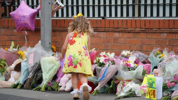 A young girl lays a tribute in Kingsheath Avenue, Liverpool, where nine-year-old Olivia Pratt-Korbel was fatally shot