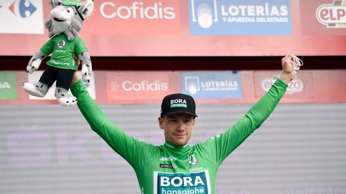 Sam Bennett celebrates on the podium wearing the overall points leader's green jersey