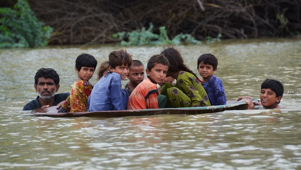 A man uses a satellite dish to move children across a flooded area in Jaffarabad district