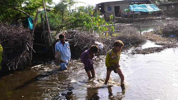Pakistani flood victims wade through flood water after a flash flood in Matiari, Sindh province