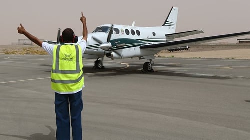 File pic from al-Ain airport of an airport employee signalling to a twin-propeller plane that is fixed with salt flares