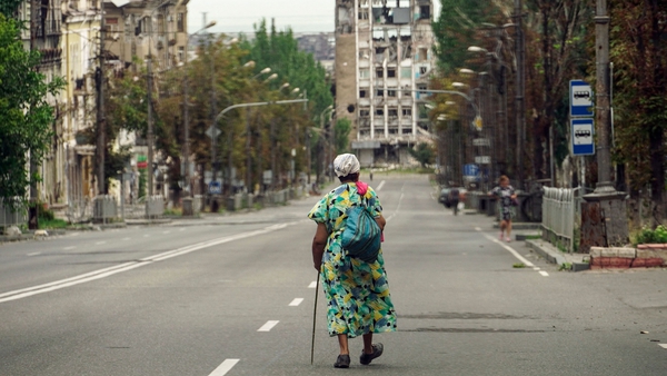 A woman walks along a ruined street in Mariupol