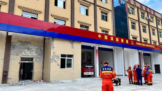 Firefighters gather near the damaged wall of a fire station in Sichuan
