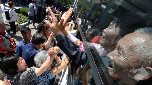 North Koreans on a bus hold hands of their South Korean relatives to bid farewell after a 2018 reunion
