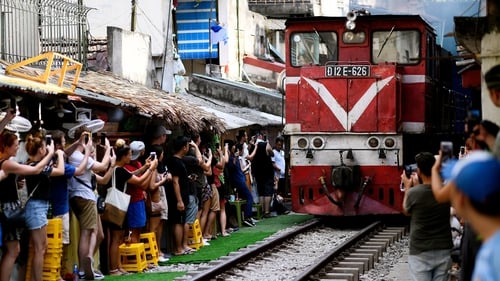 Tourists photograph a passing train in Hanoi's popular train street in 2019