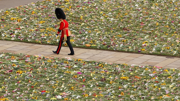 A member of the Coldstream Guards is seen walking among flowers, given by members of the public, during the queen's funeral today (Ryan Pierse/AFP)