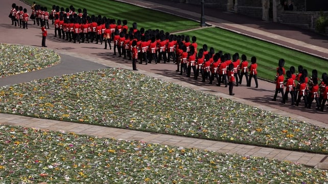 Guards prepare to line along the procession route at Windsor Castle, walking past a bed of flowers that people left for the queen (Henry Nicholls/AFP)