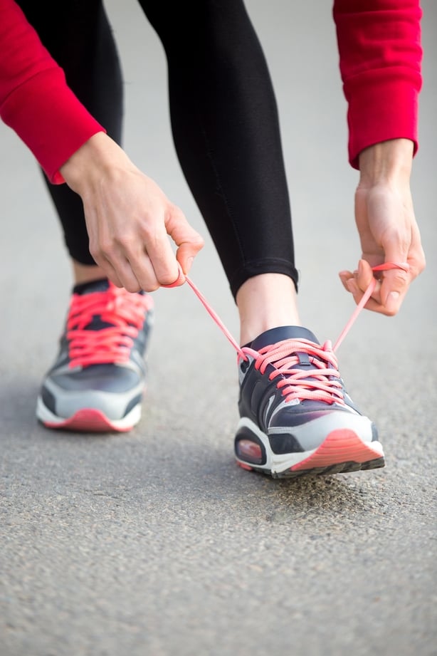 woman tying shoelace on running shoes