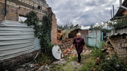 A woman walks past her house destroyed by the Russian military in the village of Moshchun near Kyiv