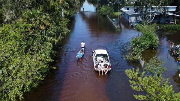 A man tows a canoe through a flooded street of his neighborhood in New Smyrna Beach, Florida
