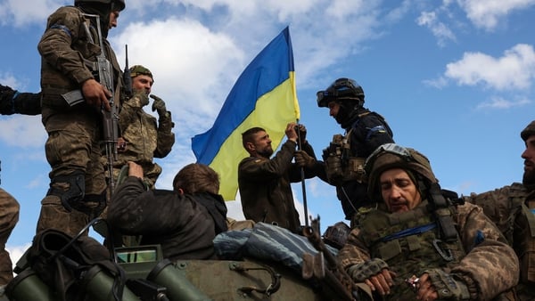Ukrainian soldiers adjust a national flag atop a personnel armoured carrier on a road near Lyman earlier this month