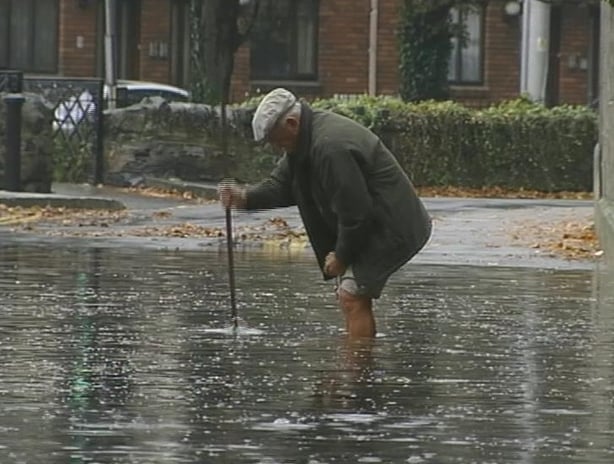 Man attempts to unblock a drain during flooding in Dublin (20020