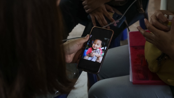 A relative holds a picture of a young child who was killed