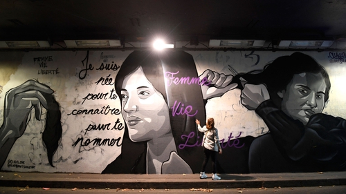 A pedestrian look at a mural in homage to Masha Amini by artist Claks in the Tunnel des Tuileries in Paris