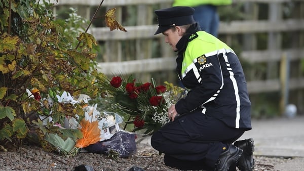 A member of An Garda Síochána lays flowers she was given by a member of the public at the scene of the explosion
