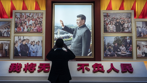 A visitor takes a photo of a display showing images of Chinese President Xi Jinping at the Museum of the Communist Party