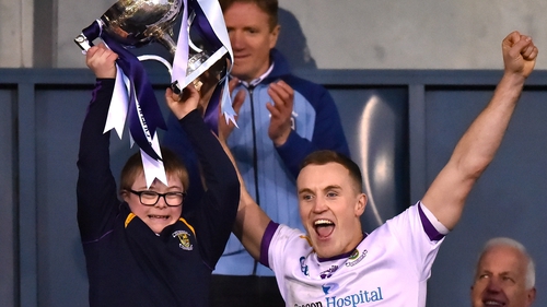 Kilmacud Crokes captain Shane Cunningham lifts the cup with supporter Connell Gallagher