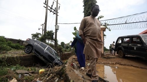 People walk past a flooded street in Abuja, Nigeria, last month