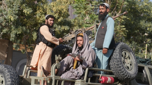Taliban fighters stand on the back of a vehicle as they conduct a 'house to house' inspection last month in Herat