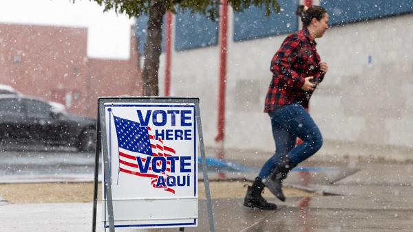A Washoe County voter runs through the snow to cast her ballot inside Reno High School in Reno, Nevada