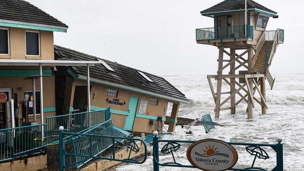 Waves crash near a damaged building and a lifeguard tower in Daytona Beach Shores in Florida