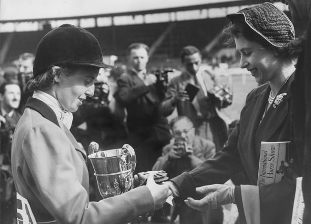 24th July 1951: A black and white photograph of a smilling Princess Elizabeth presenting the Princess Elizabeth Cup at the International Horse Show. Miss Iris Kellet won the jumping championship for lady riders. (Photo by William Vanderson/Fox Photos/Getty Images)