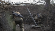 Ukrainian servicemen take cover as they fire a mortar load on the Toretsk frontline in Donbas, Ukraine