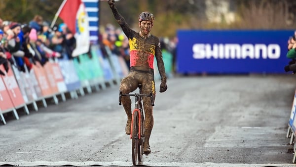 A muddy Wout van Aert crosses the finish line