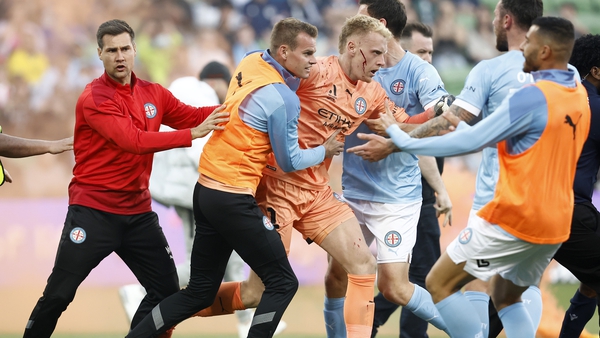 A bleeding Tom Glover of Melbourne City is escorted from the pitch by team-mates after fans stormed the pitch