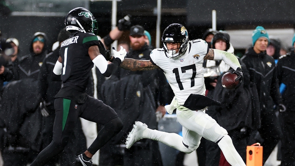 Evan Engram of the Jacksonville Jaguars carries the ball as Sauce Gardner of the New York Jets chases