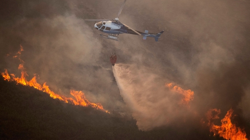 A firefighter helicopter drops water to put out a wildfire in northwestern Spain last August