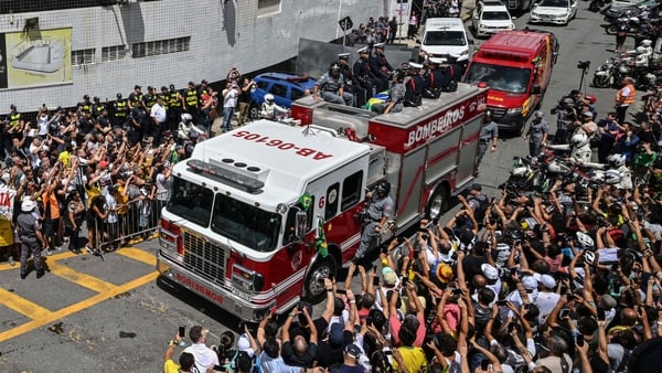 Fans line the route as Pele's body is transported through the streets to the Santos Memorial Cemetery