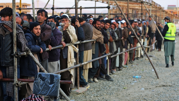 Afghan men stand in queues to receive food aid from an NGO in Kabul