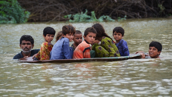A man along with a youth use a satellite dish to move children across a flooded area after heavy rainfalls in Jaffarabad district last August