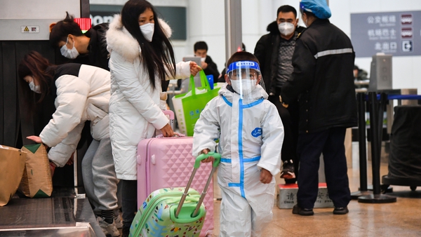 A child wearing personal protective equipment walks with a suitcase at Beijing South Railway Station during the 2023 Spring Festival travel rush