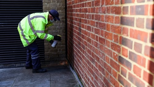 A street cleaner sprays anti-pee paint on a wall in Soho in central London