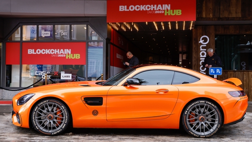 The slogan "In Crypto We Trust" on a tyre side wall on a Mercedes-Benz car outside the Blockchain Hub pavilion at Davoso