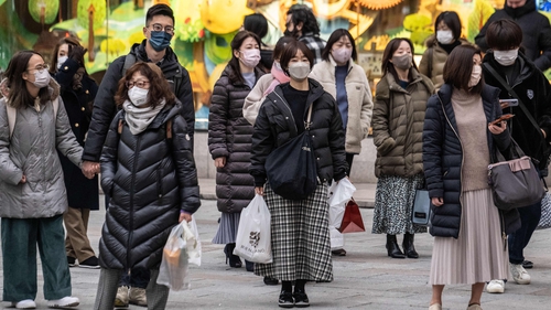 People wearing face masks wait to cross a street in Tokyo today