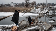 People walk on a destroyed bridge to cross a canal towards the disputed area in Bakhmut in February amid the Russian invasion of Ukraine