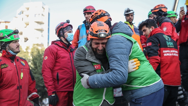Rescuers celebrate after rescuing six members of a family from under the rubble of a collapsed apartment building in Hatay, Turkey