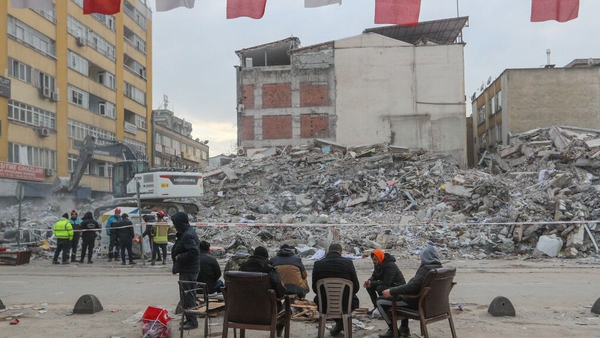 People sit around a fire among the rubble of a collapsed building in Kahramanmaras, Turkey