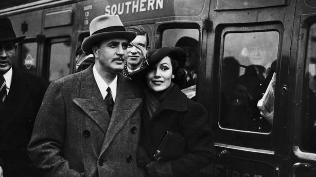 Dolores Del Rio (1905 - 1983) arriving at Waterloo station in London with her husband, MGM art director and designer of the Oscar trophy, Cedric Gibbons