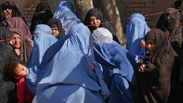 Afghan women wait to receive food aid from the Afghanistan Disaster Management in Herat