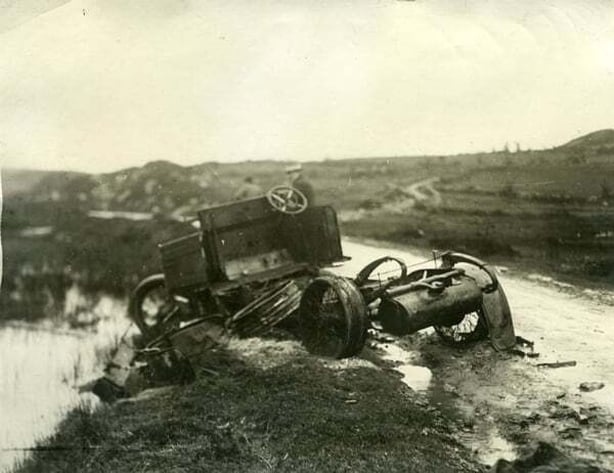 Photograph of a burned out tender on a desolate and wet country road being examined by a man in civilian dress Photo: UCD Digital Library