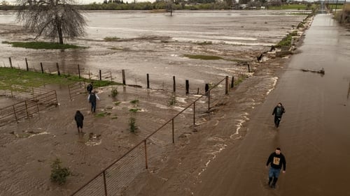 People look at the flood waters of Deer Creek near Porterville, California