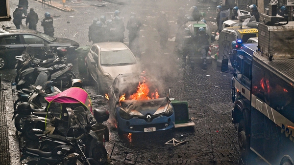 A police car is engulfed in flames on the streets of Naples