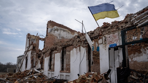 A Ukrainian flag on the wall of a destroyed school waves as the war continues