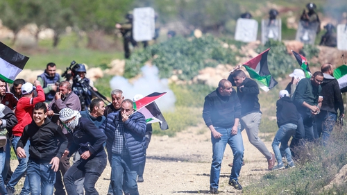 Palestinian protesters flee from tear gas canisters fired by the Israeli forces during a demonstration against settlements in the West Bank
