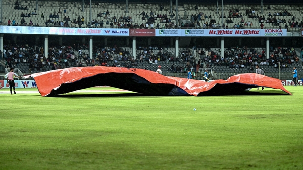 Ground staff cover the pitch with plastic sheets in Sylhet